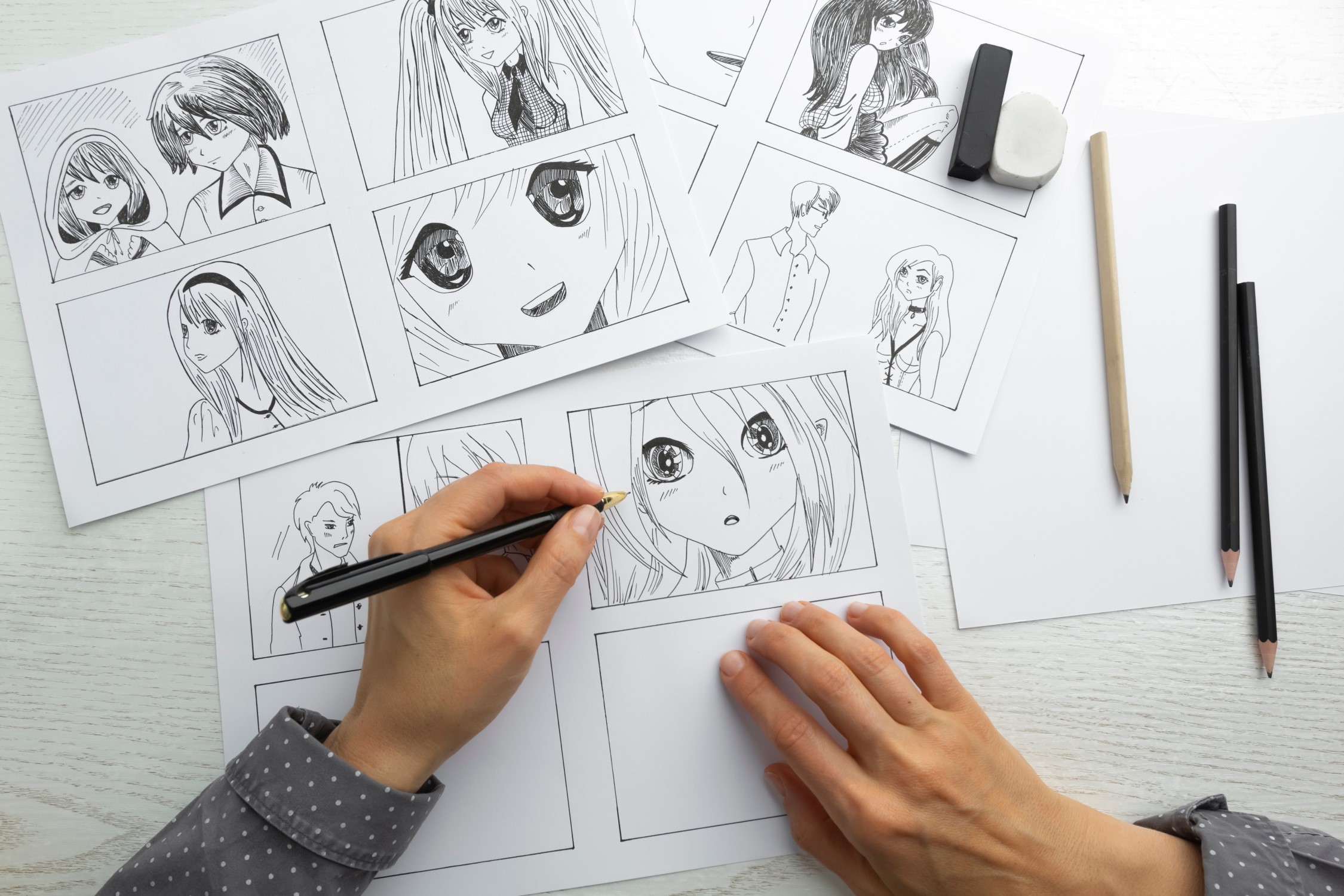 vue de dessus, des mains dessine des  visages mangas