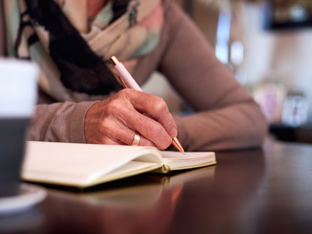 picture of someone writing on a notebook on a counter